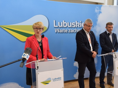 Marszałek Elżbieta Anna Polak przy mównicy. W tle szefowie szpitali.