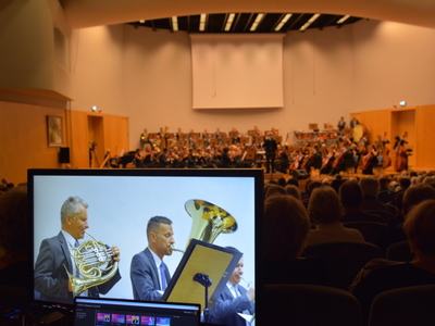 Widzowie i orkiestra w sali koncertowej.
