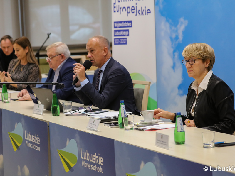 Konsultacje społeczne w sprawie Europejskich Funduszy Województwa Lubuskiego 2021-2027. Przy mikrofonie członek zarządu woj. lubuskiego, Marcin Jabłoński. Z prawej marszałek Elżbieta Anna Polak. Z lewej, członek zarządu Tadeusz Jędrzejczak oraz dyr Departamentu 	Zarządzania Regionalnym Programem Operacyjnym, Sylwia Pędzińska.