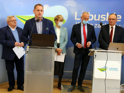 Konferencja prasowa Zarządu Województwa Lubuskiego dotycząca projektu budżetu na 2022 rok. Przy mikrofonie wicemarszałek Łukasz Porycki. Z tyłu od lewej stoją: członek zarządu Tadeusz Jędrzejczak, marszałek Elżbieta Anna Polak, członek zarządu Marcin Jabłoński oraz wicemarszałek Stanisław Tomczyszyn.