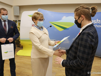 Marszałek Elżbieta Anna Polak oraz wicemarszałek Łukasz Porycki wręczają studentowi stypendium motywujące
