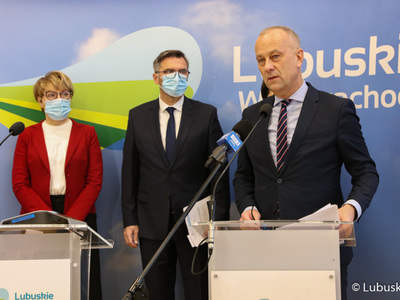 Członek zarządu woj. lubuskiego, Marcin Jabłoński (przy mikrofonie) podczas konferencji prasowej w sprawie budowy lubuskich obwodnic. Z tyłu od lewej stoją: marszałek Elżbieta Anna Polak oraz poseł na Sejm RP Waldemar Sługocki. 