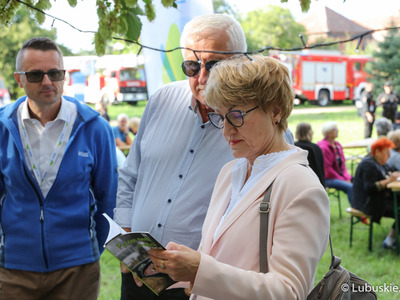 Marszałek woj. lubuskiego Elżbieta Anna Polak, burmistrz Kożuchowa Paweł Jagasek oraz Senator RP Wadim Tyszkiewicz odwiedzają jedno ze stoisk Kół Gospodyń Wiejskich na Święcie Województwa Lubuskiego w Kożuchowie