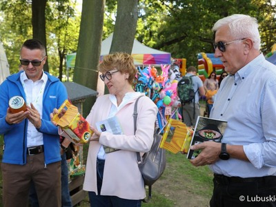 Marszałek woj. lubuskiego Elżbieta Anna Polak, burmistrz Kożuchowa Paweł Jagasek (z lewej) oraz Senator RP Wadim Tyszkiewicz odwiedzają jedno ze stoisk Kół Gospodyń Wiejskich na Święcie Województwa Lubuskiego w Kożuchowie