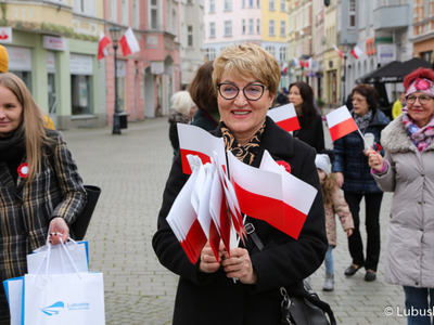 Marszałek Województwa Lubuskiego Elżbieta Anna Polak rozdaje biało-czerwone chorągiewki uczestnikom Marszu Niepodległości w Zielonej Górze