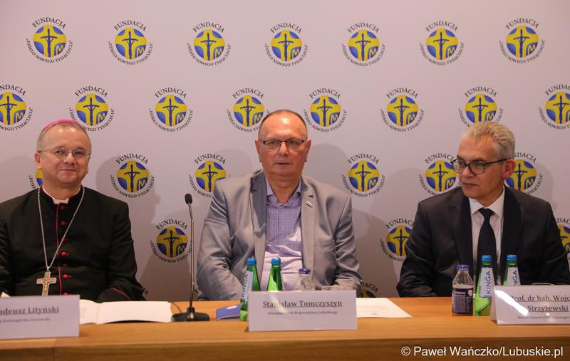 Podczas konferencji prasowej w parafii pw. Ducha Świętego w Zielonej Górze wicemarszałek Stanisław Tomczyszyn (w środku) podkreślał, że cieszy się, że te kilkaset osób przybyło do regionu lubuskiego. To są osoby, które otrzymują wsparcie z fundacji "Dzieło Nowego Tysiąclecia". Z lewej bp. Tadeusz Lityński – ordynariusz zielonogórsko-gorzowski,  z prawej prof. dr hab. Wojciech Strzyżewski – Rektor Uniwersytetu Zielonogórskiego.