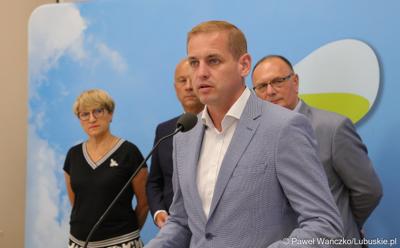 Wicemarszałek Województwa Lubuskiego Łukasz Porycki przemawia podczas konferencji prasowej. Z tyłu stoją (od lewej): Marszałek Województwa Lubuskiego Elżbieta Anna Polak, Członek Zarządu Województwa Lubuskiego Marcin Jabłoński oraz Wicemarszałek Województwa Lubuskiego Stanisław Tomczyszyn.