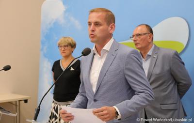 Wicemarszałek Województwa Lubuskiego Łukasz Porycki przemawia podczas konferencji prasowej. Z tyłu stoją (od lewej): Marszałek Województwa Lubuskiego Elżbieta Anna Polak oraz Wicemarszałek Województwa Lubuskiego Stanisław Tomczyszyn.
