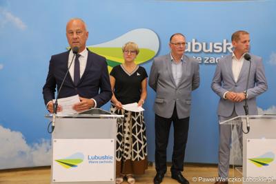 Członek Zarządu Województwa Lubuskiego Marcin Jabłoński przemawia podczas konferencji prasowej. Z tyłu stoją (od lewej): Marszałek Województwa Lubuskiego Elżbieta Anna Polak,  Wicemarszałek Województwa Lubuskiego Stanisław Tomczyszyn oraz Wicemarszałek Województwa Lubuskiego Łukasz Porycki.