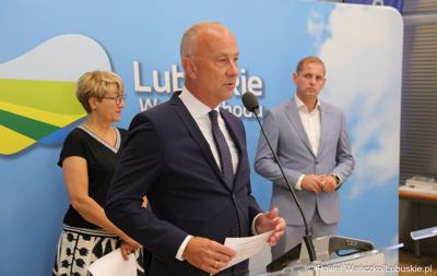 Członek Zarządu Województwa Lubuskiego Marcin Jabłoński przemawia podczas konferencji prasowej. Z tyłu stoją (od lewej): Marszałek Województwa Lubuskiego Elżbieta Anna Polak oraz Wicemarszałek Województwa Lubuskiego Łukasz Porycki.