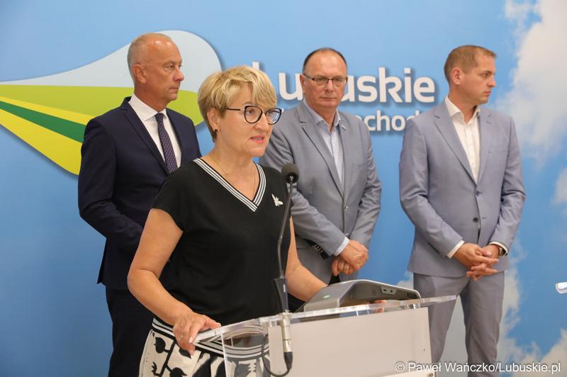 Marszałek Województwa Lubuskiego Elżbieta Anna Polak (przy mikrofonie) przemawia na konferencji prasowej. Z tyłu stoją (od lewej): Członek Zarządu Województwa Lubuskiego Marcin Jabłoński,  Wicemarszałek Województwa Lubuskiego Stanisław Tomczyszyn oraz Wicemarszałek Województwa Lubuskiego Łukasz Porycki.