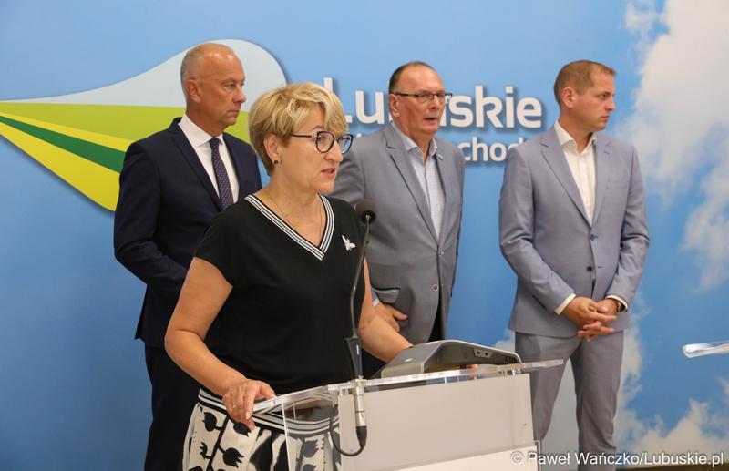 Marszałek Województwa Lubuskiego Elżbieta Anna Polak (przy mikrofonie) przemawia na konferencji prasowej. Z tyłu stoją (od lewej): Członek Zarządu Województwa Lubuskiego Marcin Jabłoński,  Wicemarszałek Województwa Lubuskiego Stanisław Tomczyszyn oraz Wicemarszałek Województwa Lubuskiego Łukasz Porycki.