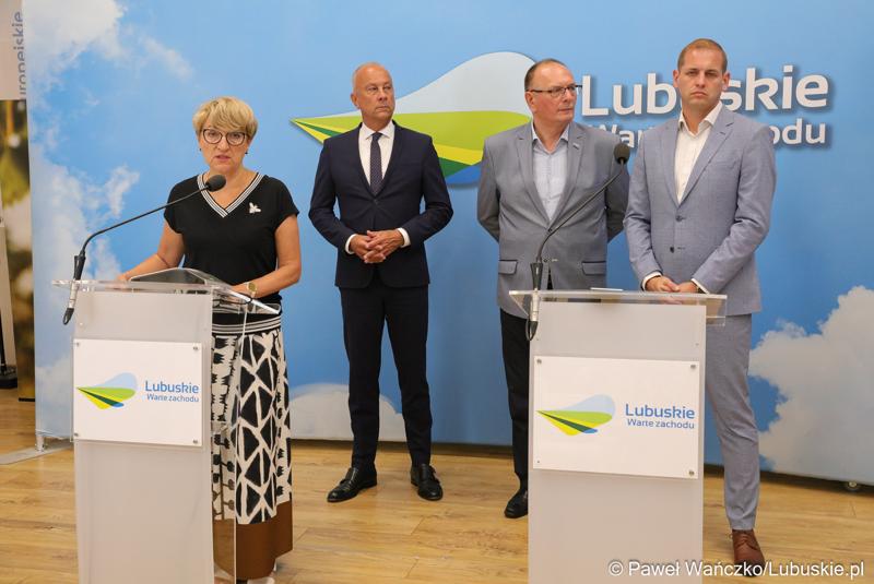 Marszałek Województwa Lubuskiego Elżbieta Anna Polak (przy mikrofonie) przemawia na konferencji prasowej. Z tyłu stoją (od lewej): Członek Zarządu Województwa Lubuskiego Marcin Jabłoński,  Wicemarszałek Województwa Lubuskiego Stanisław Tomczyszyn oraz Wicemarszałek Województwa Lubuskiego Łukasz Porycki.