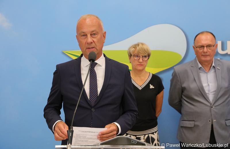 Członek Zarządu Województwa Lubuskiego Marcin Jabłoński przemawia podczas konferencji prasowej. Z tyłu stoją (od lewej): Marszałek Województwa Lubuskiego Elżbieta Anna Polak oraz Wicemarszałek Województwa Lubuskiego Stanisław Tomczyszyn.