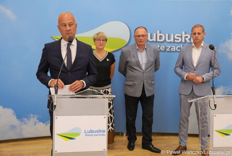 Członek Zarządu Województwa Lubuskiego Marcin Jabłoński przemawia podczas konferencji prasowej. Z tyłu stoją (od lewej): Marszałek Województwa Lubuskiego Elżbieta Anna Polak,  Wicemarszałek Województwa Lubuskiego Stanisław Tomczyszyn oraz Wicemarszałek Województwa Lubuskiego Łukasz Porycki.