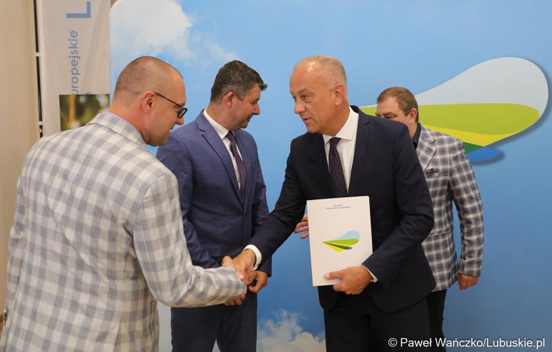 Członek Zarządu Województwa Lubuskiego Marcin Jabłoński (z prawej) wręcza umowy przedstawicielom gmin i lubuskich powiatów