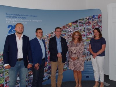 Grupa osób pozuje do zdjęcia na tle ścianki.