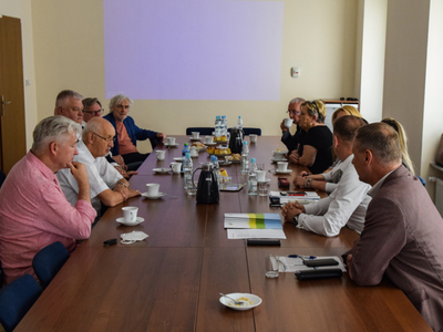 Zdjęcie ze spotkania; osoby rozmawiające przy stole w sali konferencyjnej.