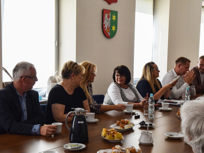 Zdjęcie ze spotkania; osoby rozmawiające przy stole w sali konferencyjnej.
