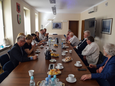 Zdjęcie ze spotkania; osoby rozmawiające przy stole w sali konferencyjnej.