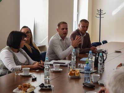 Zdjęcie ze spotkania; osoby rozmawiające przy stole w sali konferencyjnej.