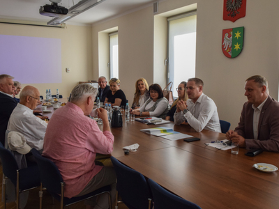 Zdjęcie ze spotkania; osoby rozmawiające przy stole w sali konferencyjnej.