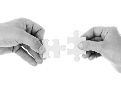Dwie dłonie trzymające puzzle.