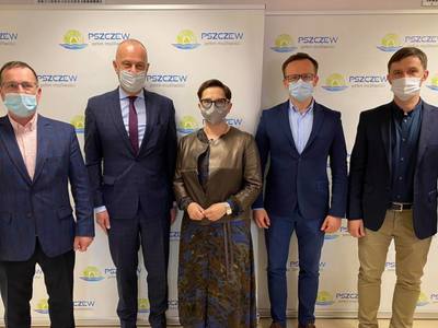 Pięć osób na tle ścianki promocyjnej gminy Pszczew.