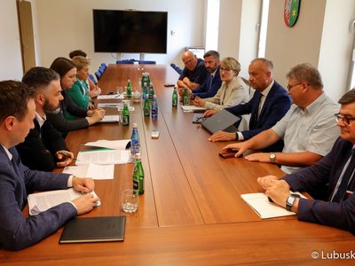 Uczestnicy spotkania siedzą przy stole i rozmawiają.