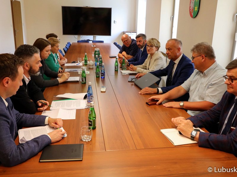 Uczestnicy spotkania siedzą przy stole i rozmawiają.