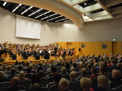 Sala koncertowa w Filharmonii z widzami i orkiestrą.