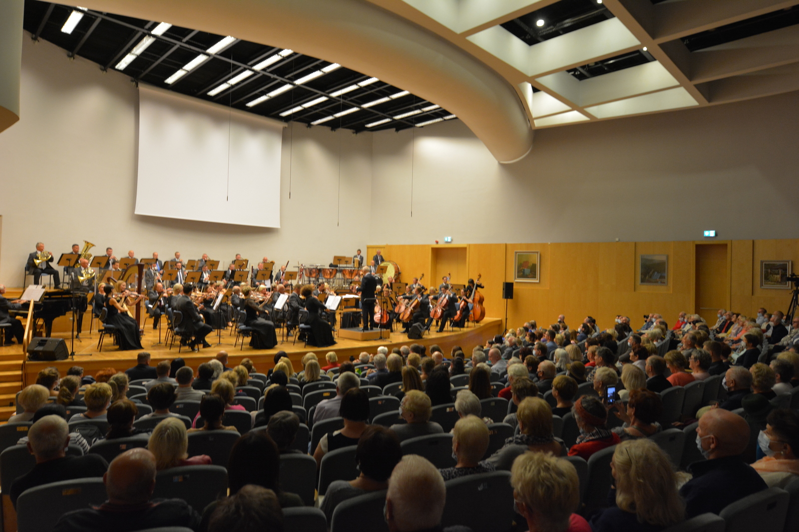 Sala koncertowa w Filharmonii z widzami i orkiestrą.