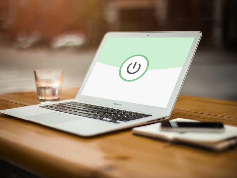 Na zdjęciu widać otwarty laptop, otwarty kalendarz, telefon komórkowy i szklankę z wodą. Zdjęcie ma obrazować domowe stanowisko pracy podczas pracy zdalnej.